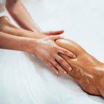 Leg massage. Physical therapyst massaging leg of young male athelete
