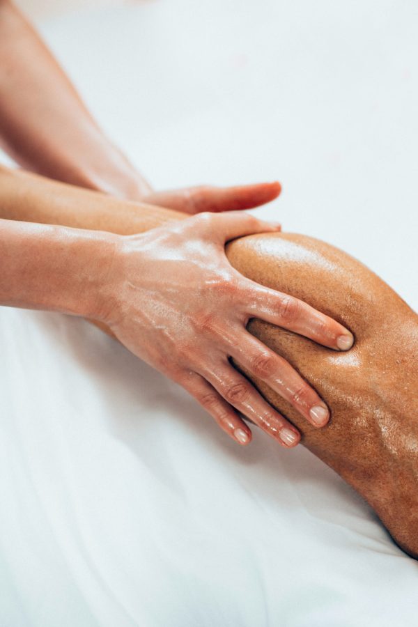 Leg massage. Physical therapyst massaging leg of young male athelete