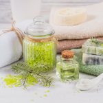 Natural cosmetic oil, sea salt, facial mask and natural handmade soap with coniferous extract on white rustic wooden background. Healthy skin, facial and body care. SPA and sauna concept.