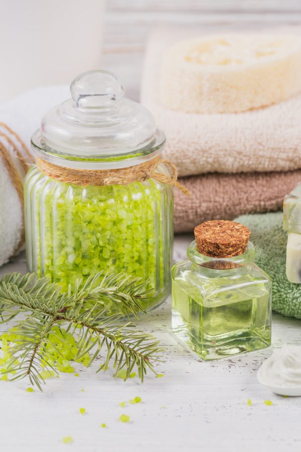 Natural cosmetic oil, sea salt, facial mask and natural handmade soap with coniferous extract on white rustic wooden background. Healthy skin, facial and body care. SPA and sauna concept.